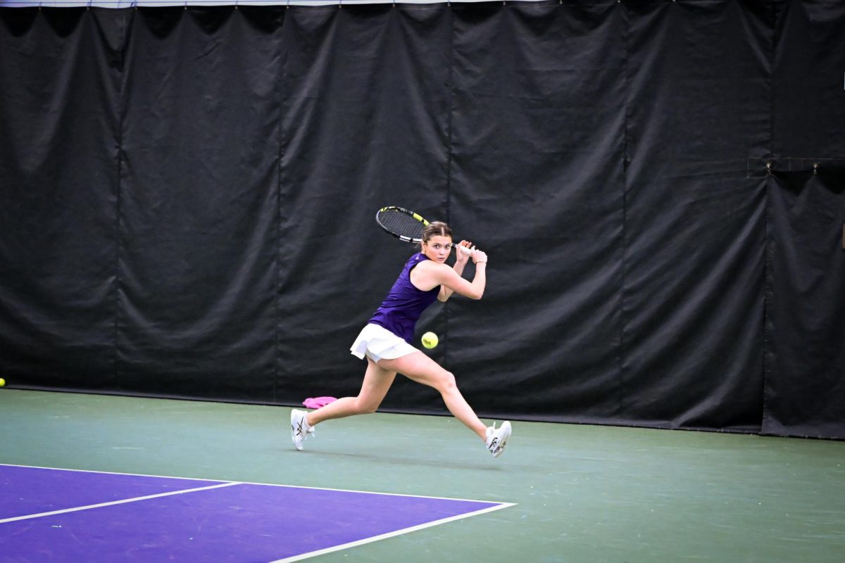 A tennis player reaches to hit a forehand.