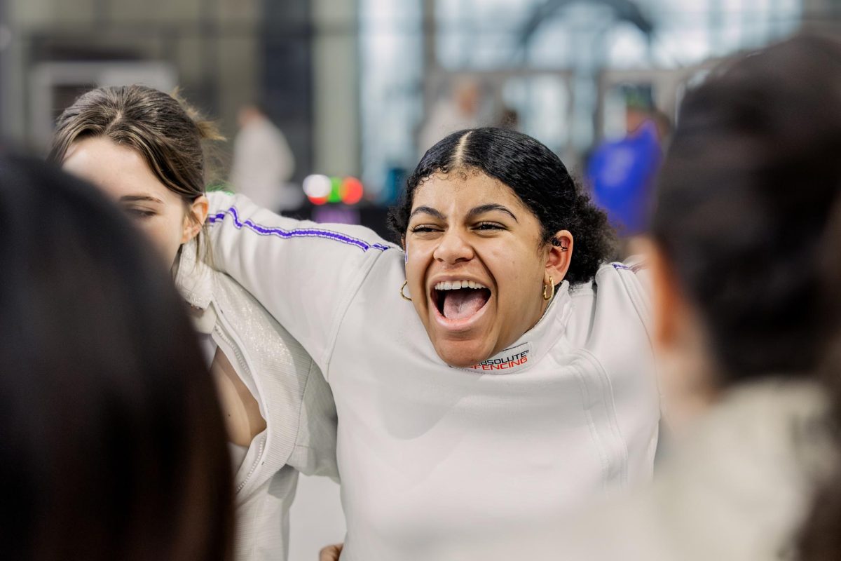 A Northwestern fencer shouts while gathered in a huddle.