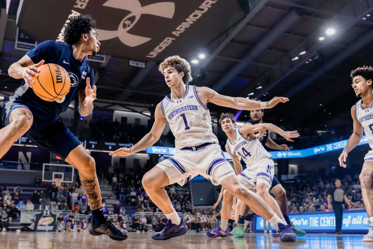 A Northwestern basketball player spreads their arms wide on defense.