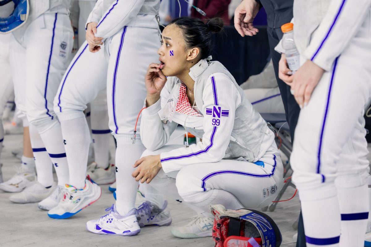 A Northwestern fencer squats down with a concerned stare while watching someone off-camera.