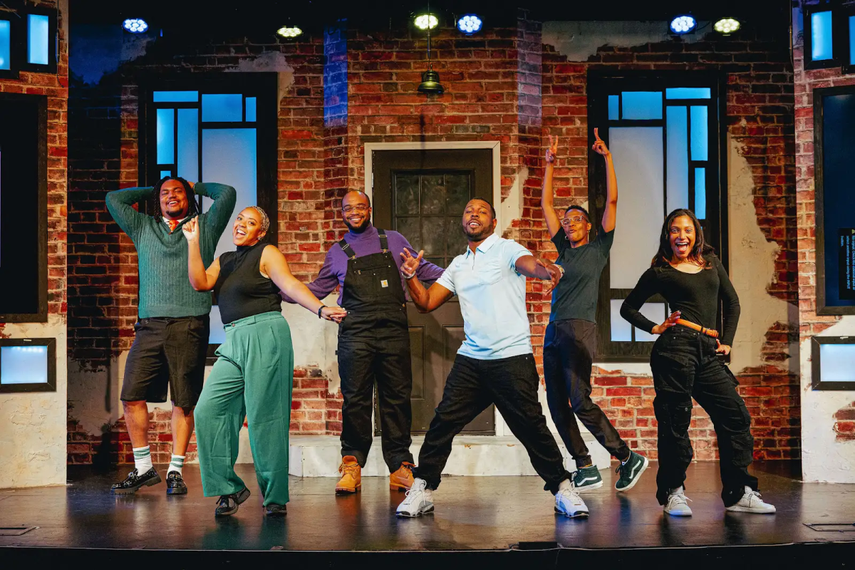 Six comedians pose on a brightly lit stage.