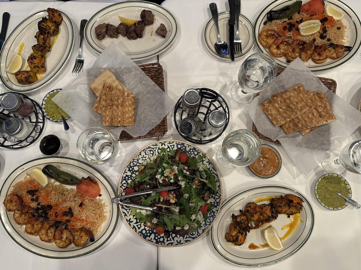 Multiple Afghan dishes are spread out across a table on white and black plates.