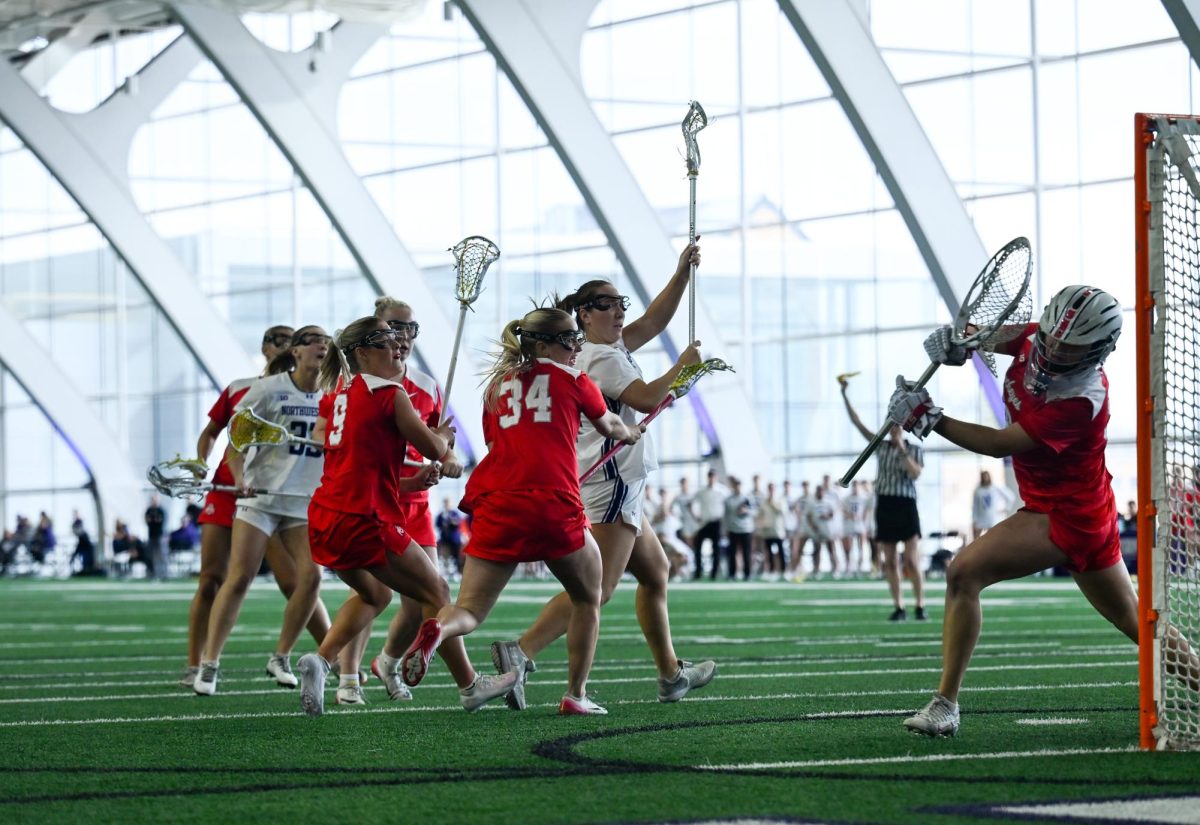 A player in a white jersey watches their shot while players in red try to defend.