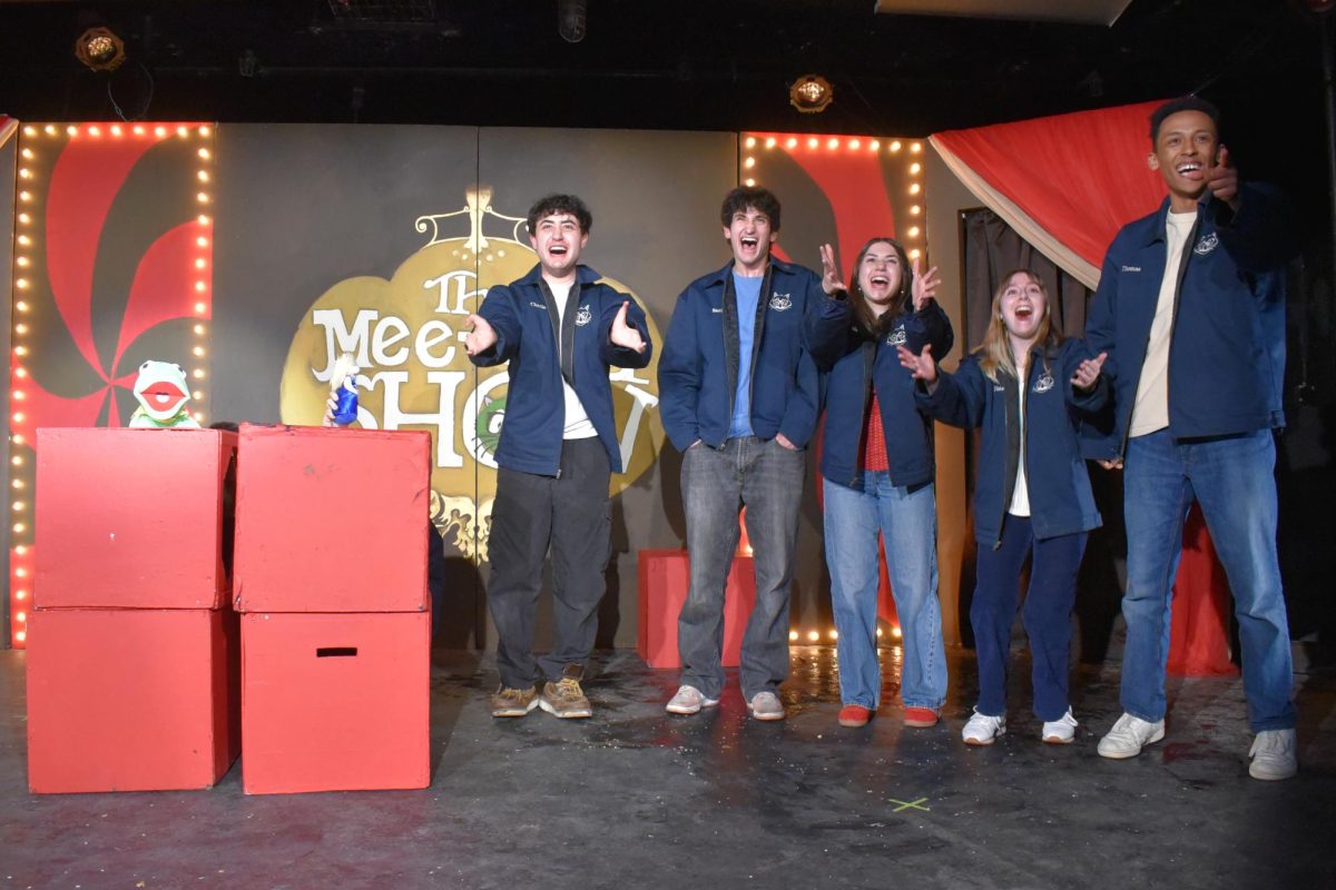 A line of people onstage smile and hold out their hands.