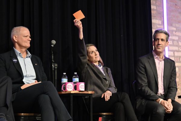 Person holds up a piece of paper while sitting between two other people.