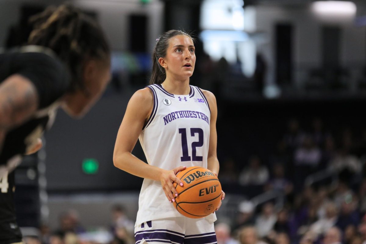 A person in a white jersey holds a basketball and looks up.