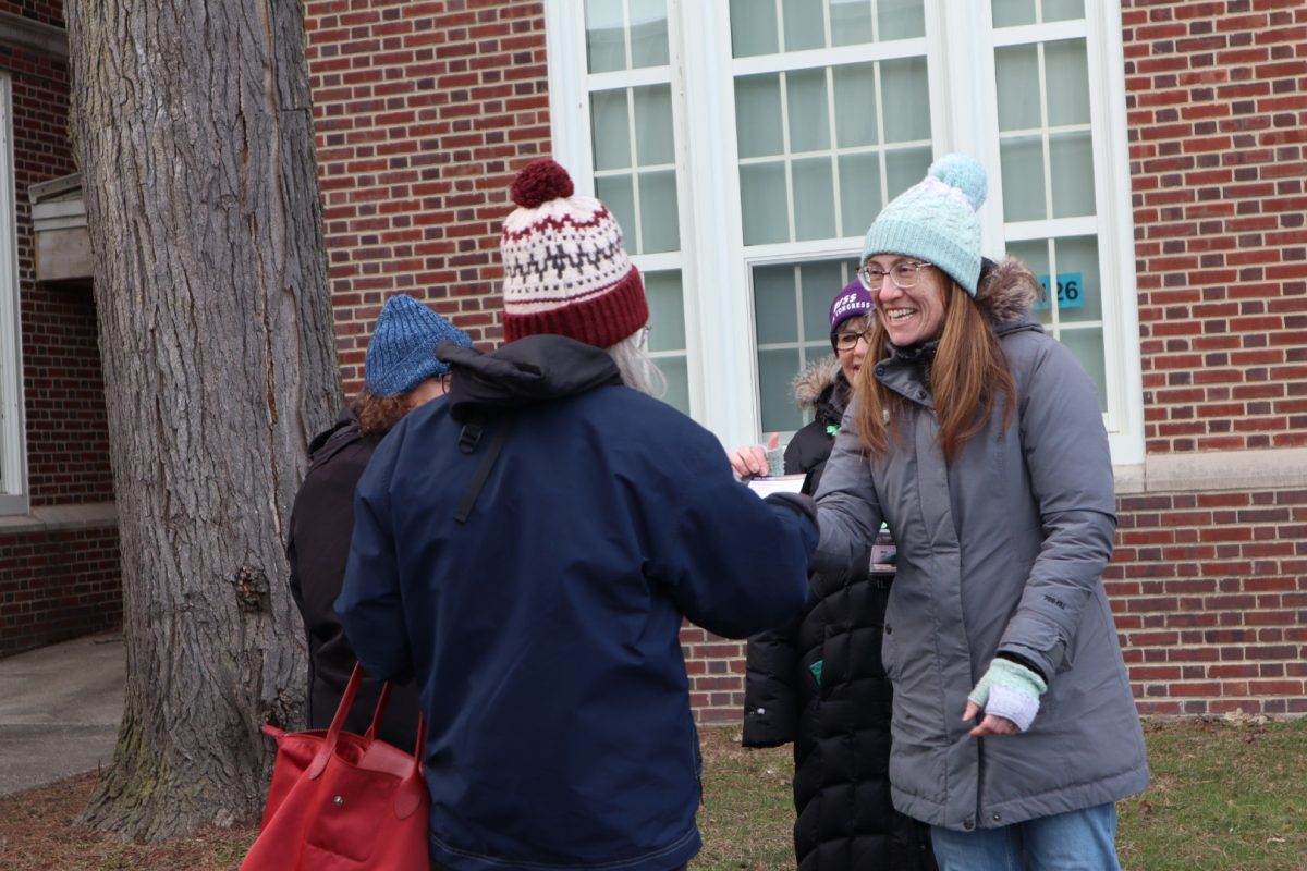 Two people shake hands with one another outside of a building.