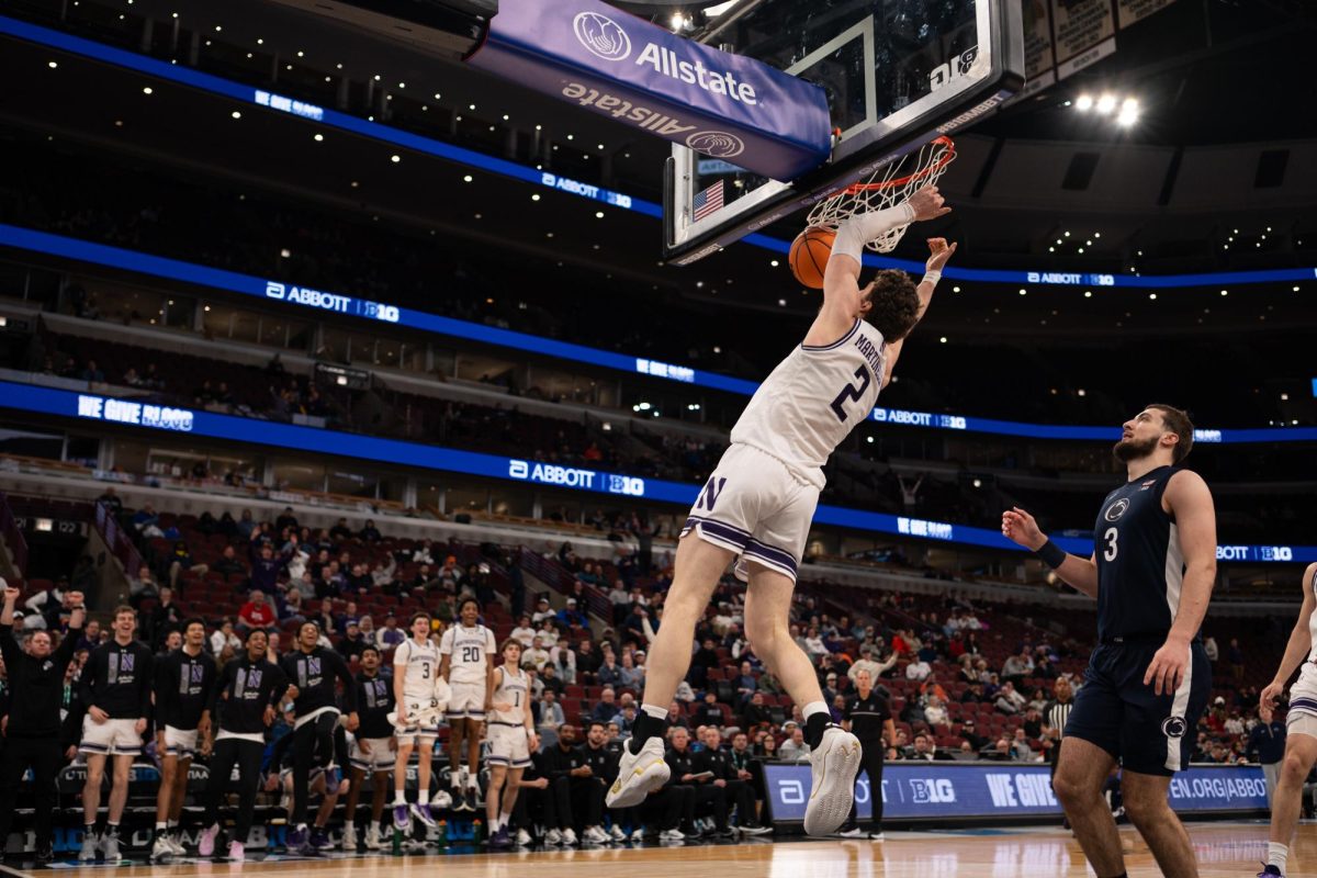 A player in a white jersey dunks the ball while an opposing player watches.