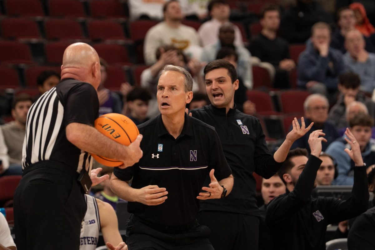 Two coaches wearing black look angrily at a referee. 