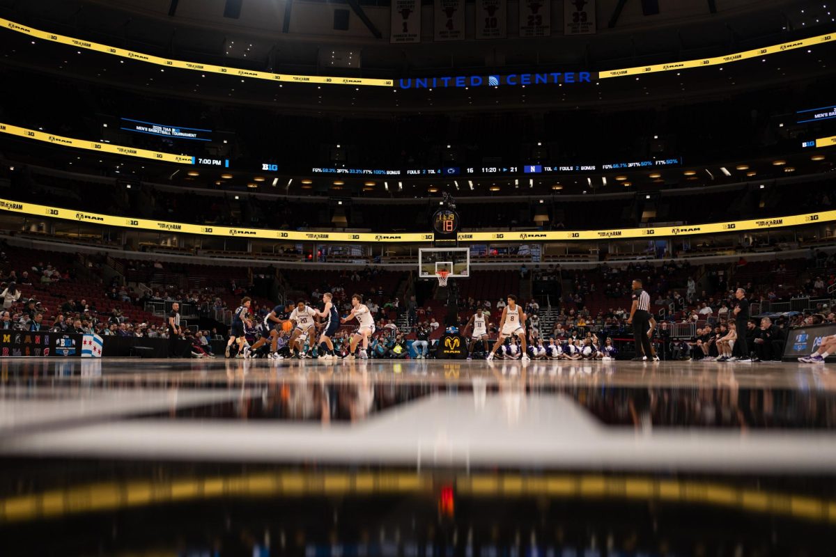 A wide shot of a basketball arena, with basketball players in blue and white jerseys. 