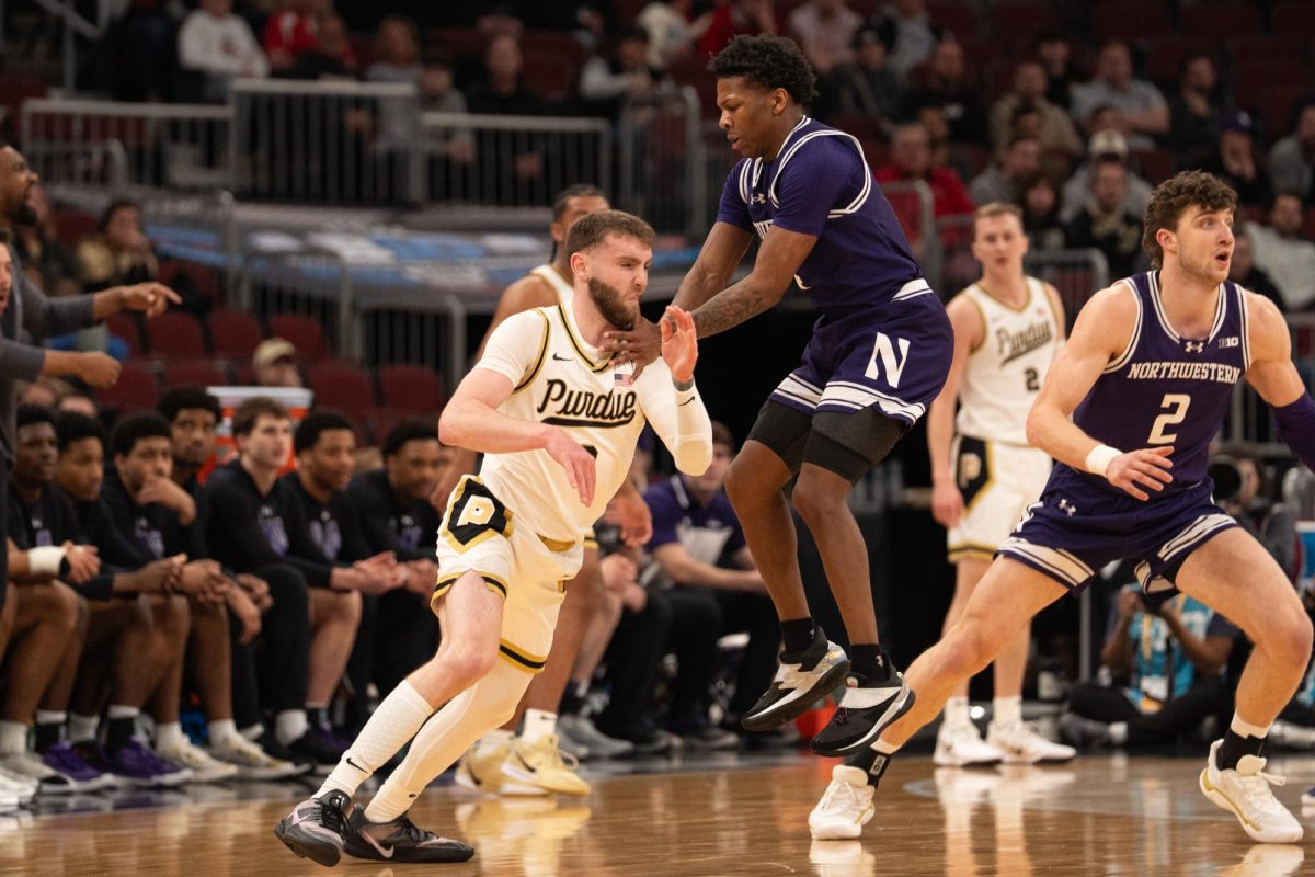 A player in a purple jersey jumps while holding their opponent.