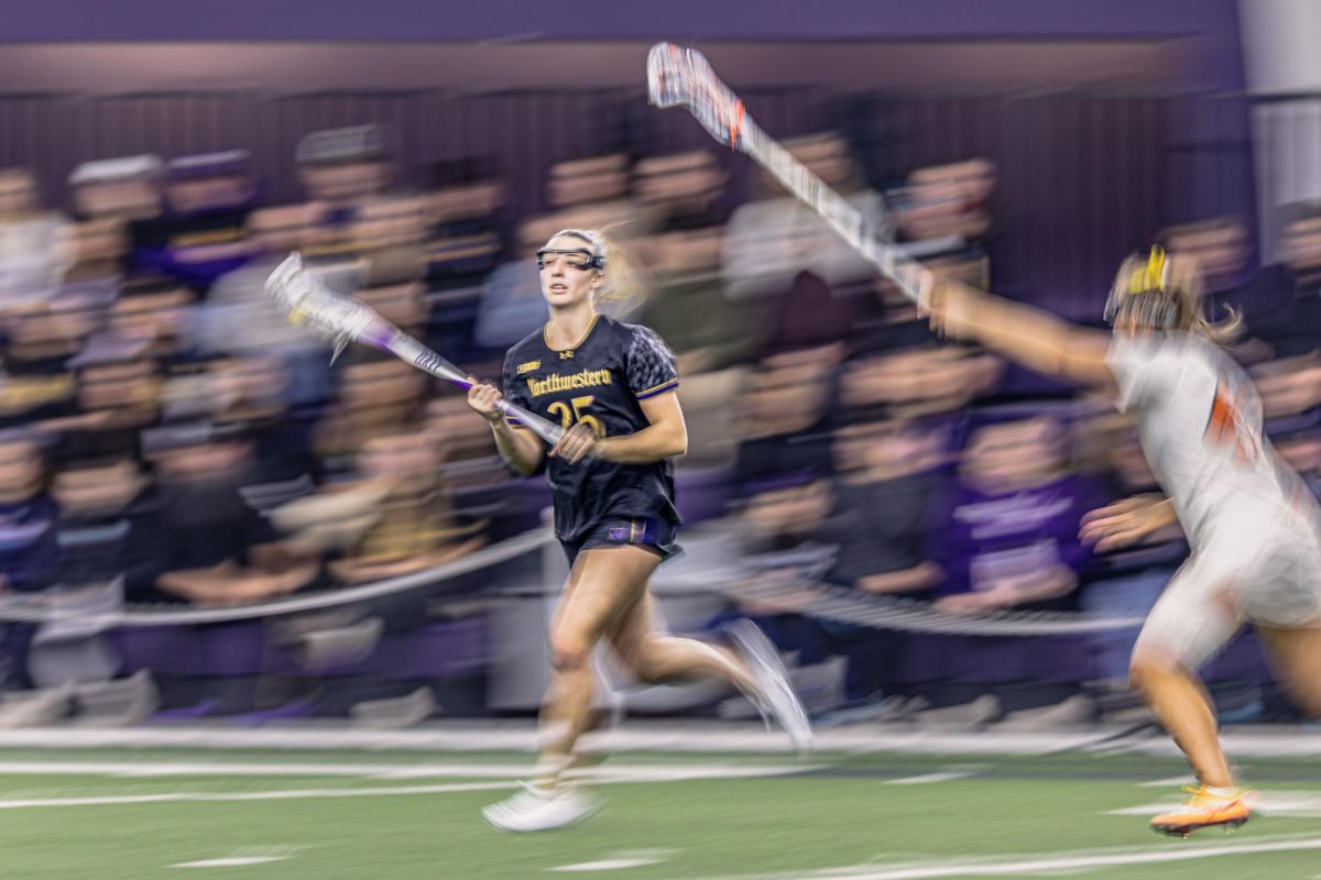 A blurry Northwestern player runs down the field with their stick in the air.