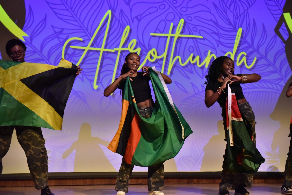 Dancers on stage hold up hearts and different countries' flags.