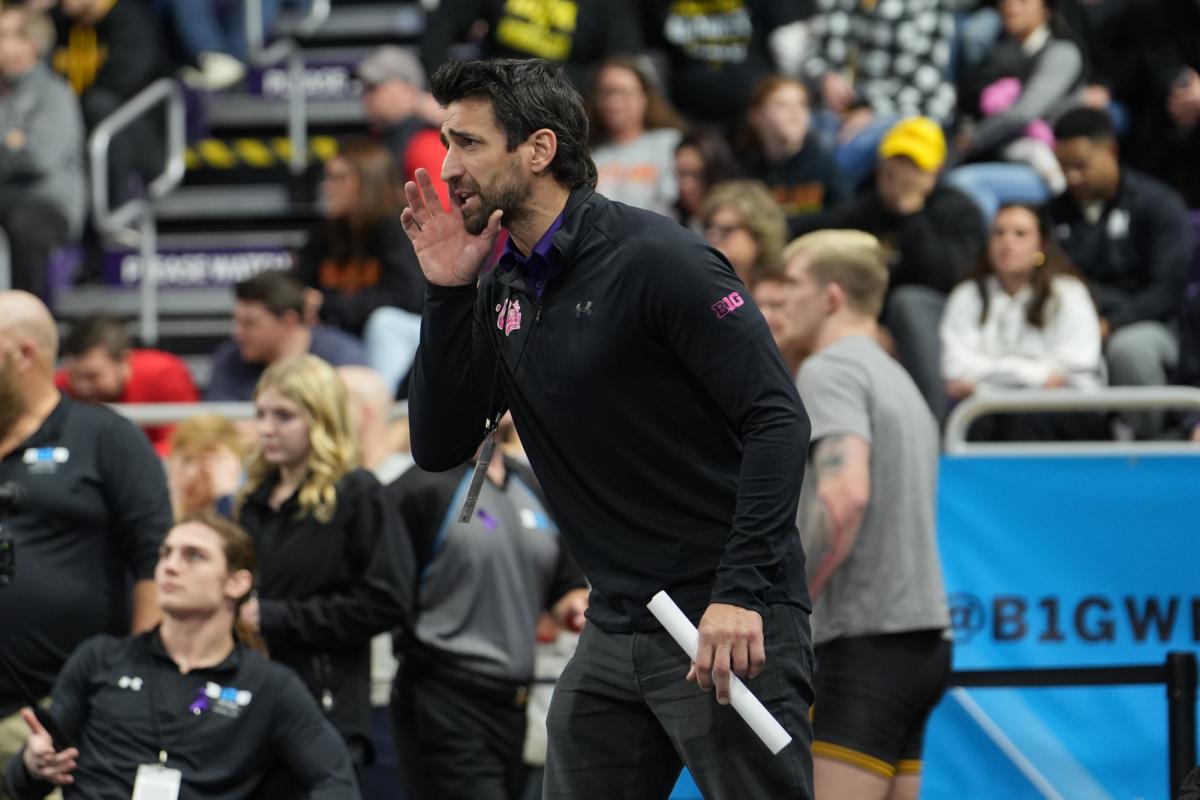 A man in a black jacket speaks, looking at something out of frame.