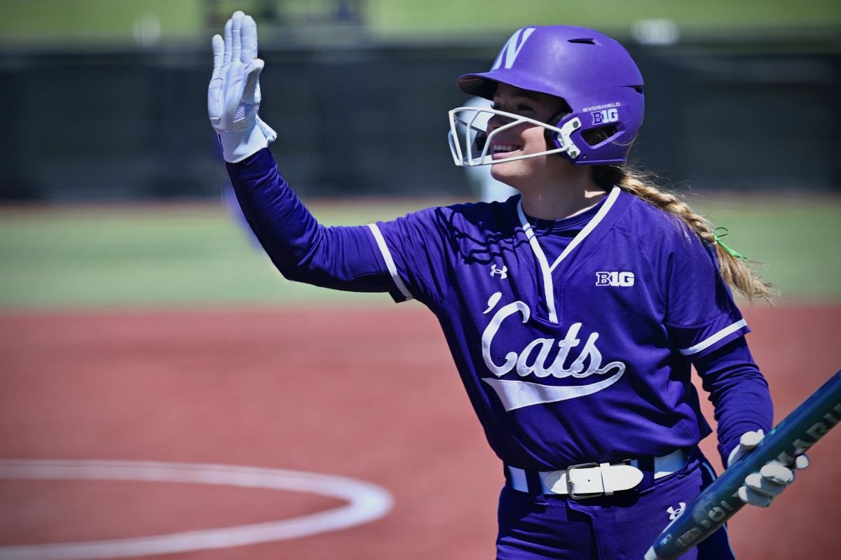 A player in white waves to the crowd after scoring a run.