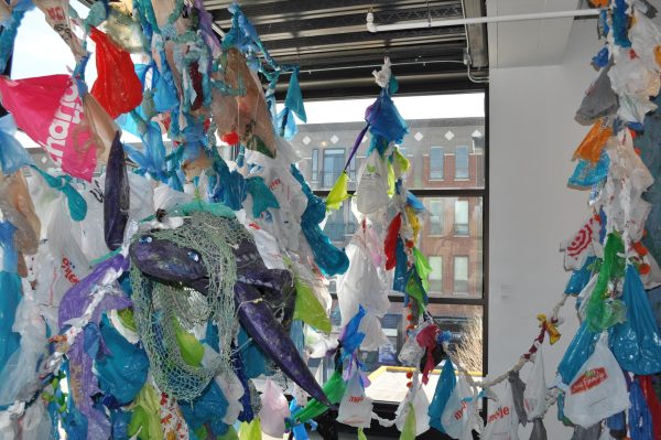A purple paper sea turtle and columns of plastic bags hang from a ceiling.