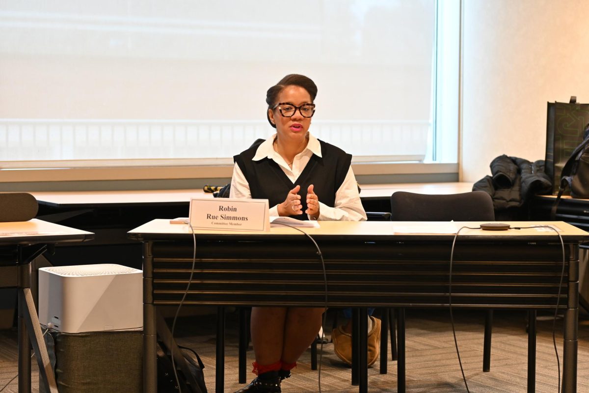A woman sits at a black desk with a name card in front of her.