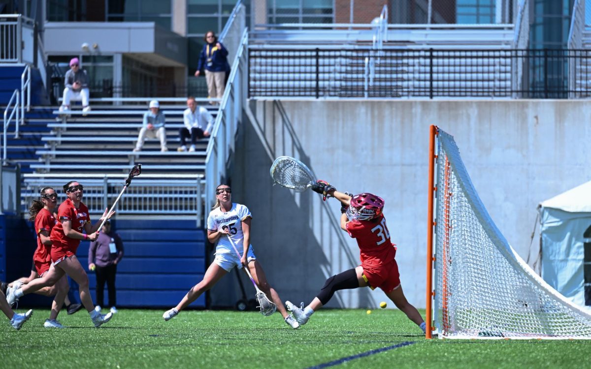 A player in white shoots a ball while a player in red tries to defend.
