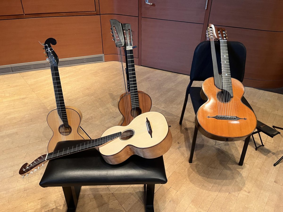 A guitar on a bench with three guitars propped up behind it