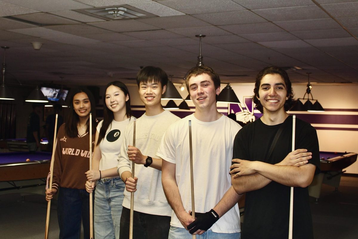Members of the Billiards Club executive team pose in front of pool tables.