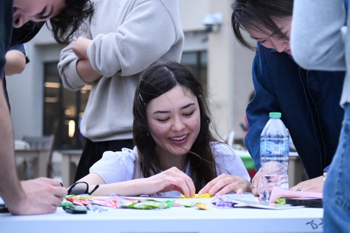 A person smiles while folding a sheet of paper.