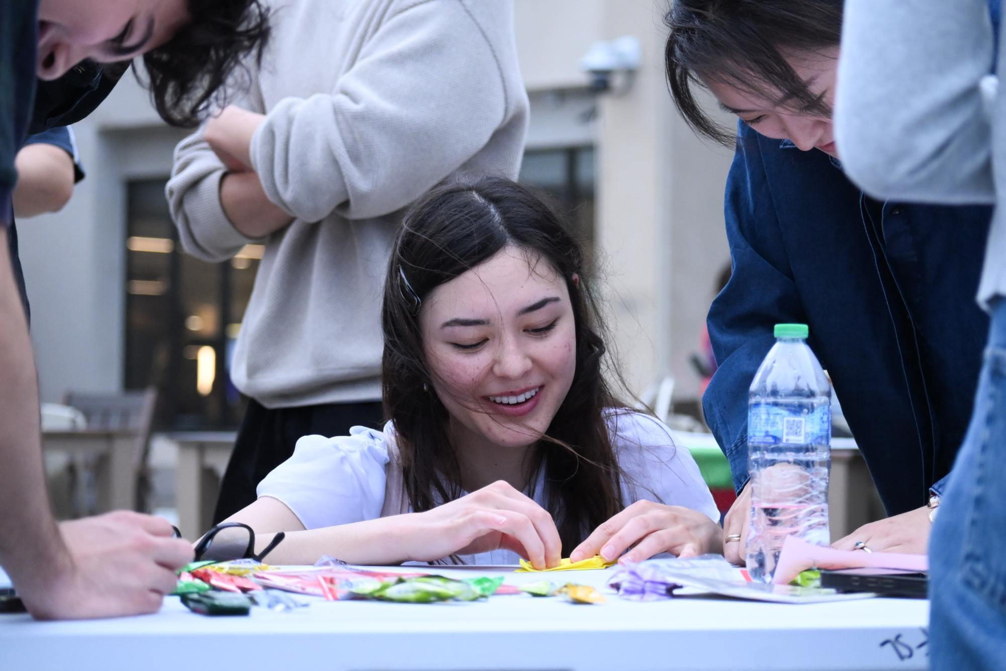 A person smiles while folding a sheet of paper.
