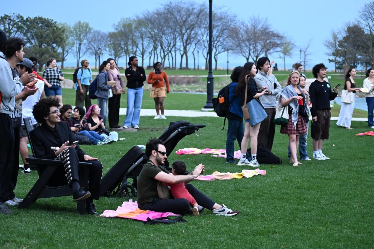 People sit and stand on the lawn.