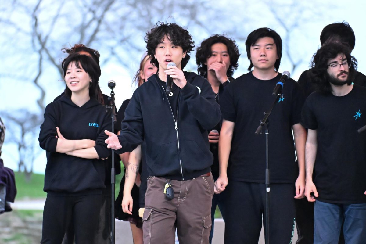 A person holds a microphone while others stand in the background. 