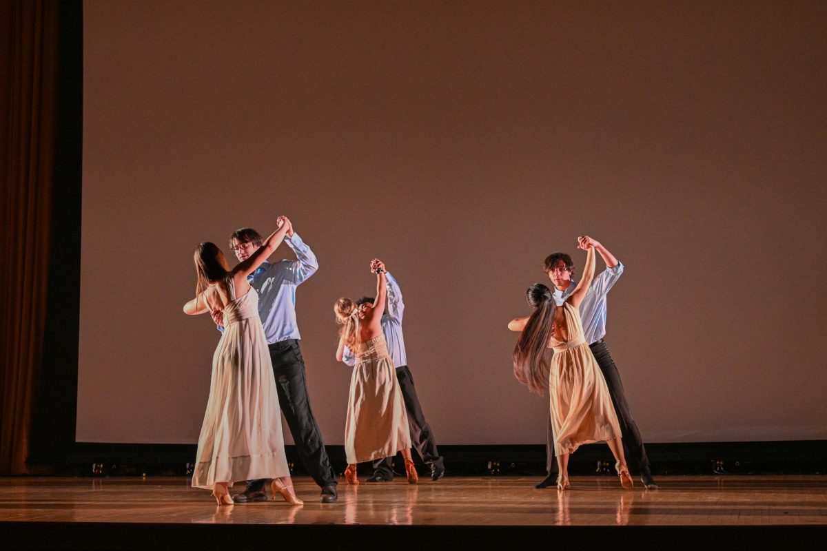 Three pairs of dancers, with one dancer extending their arms out to their partner.