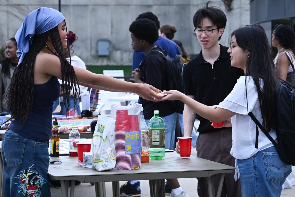A person standing behind a table hands an object to another person. 