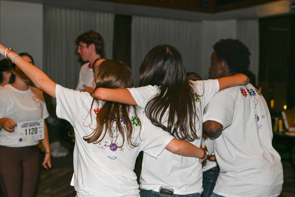 Students stand with arms around each other.