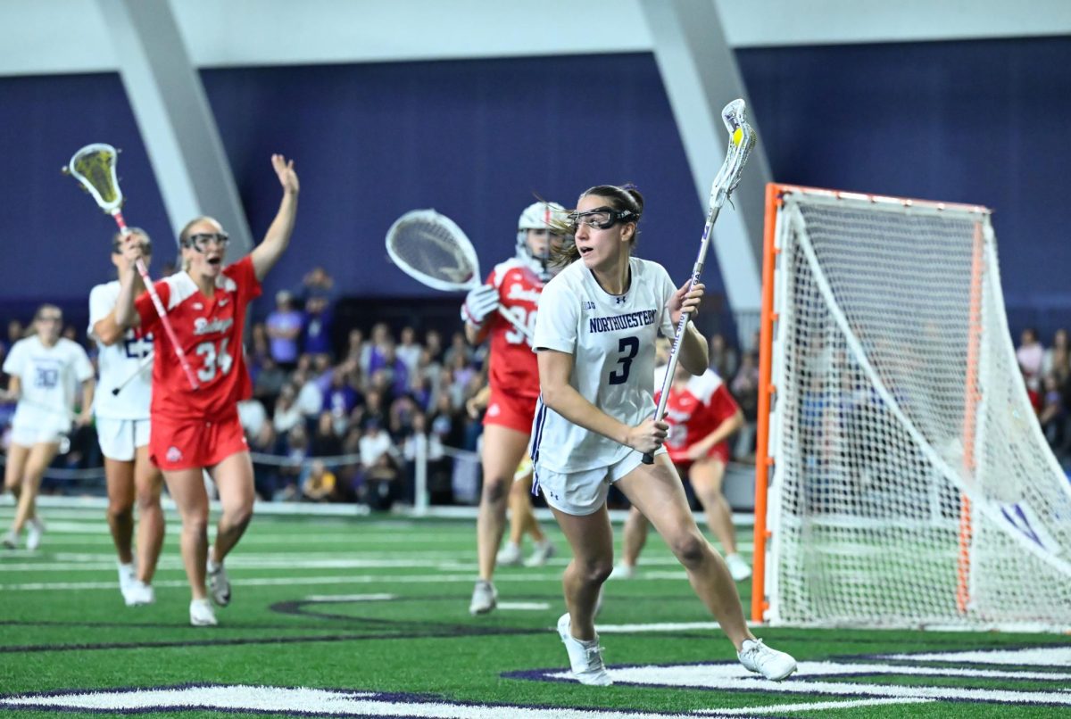 A lacrosse player looks to the side while cradling the ball.