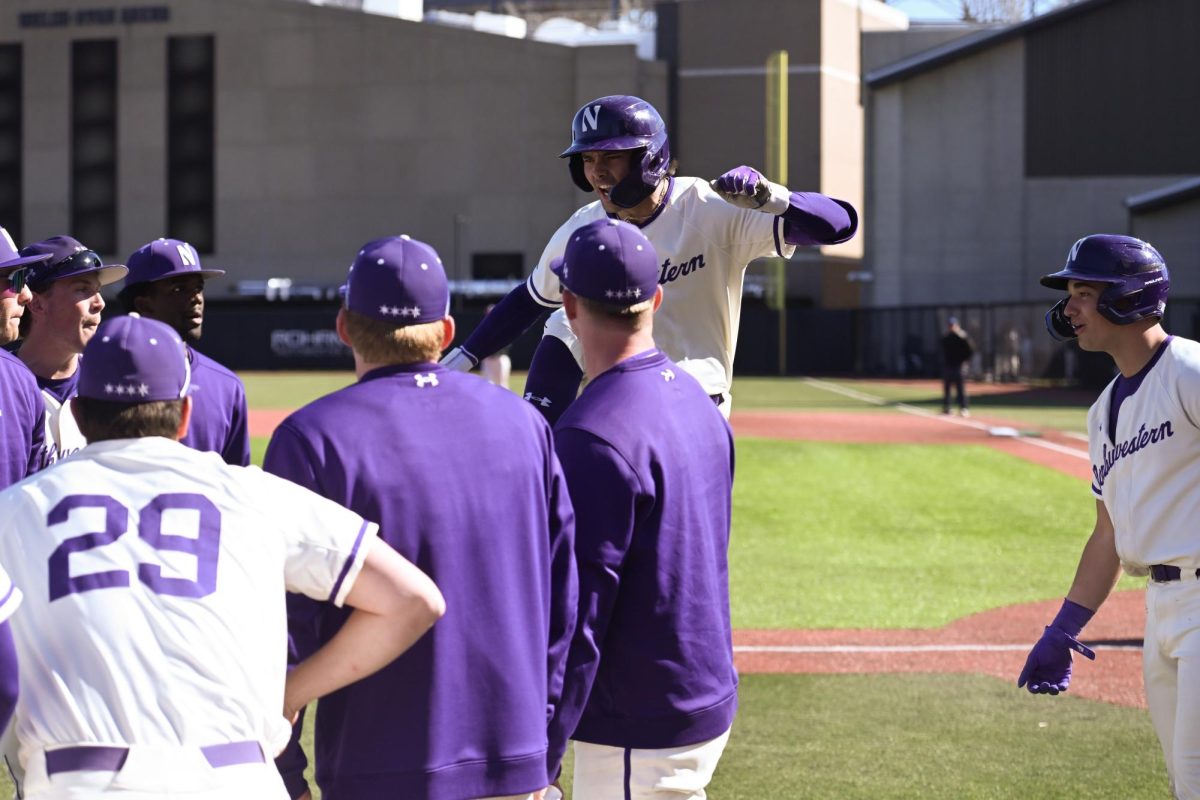 Northwestern baseball player jumps in air in front of teammates.