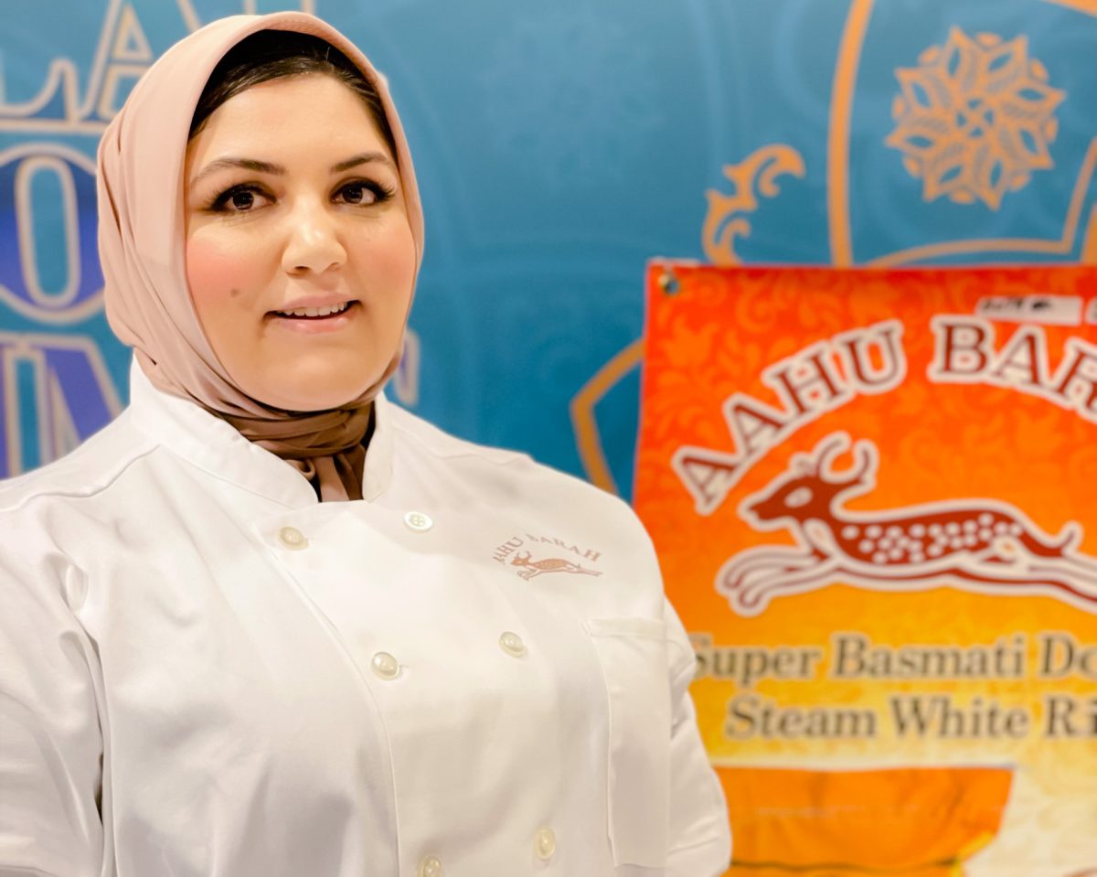 A person in a chef jacket in front of a blue and orange background