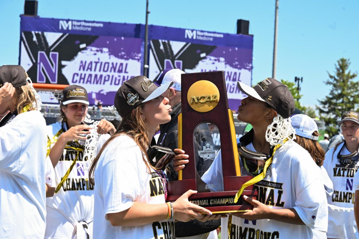 Two players kiss a trophy.