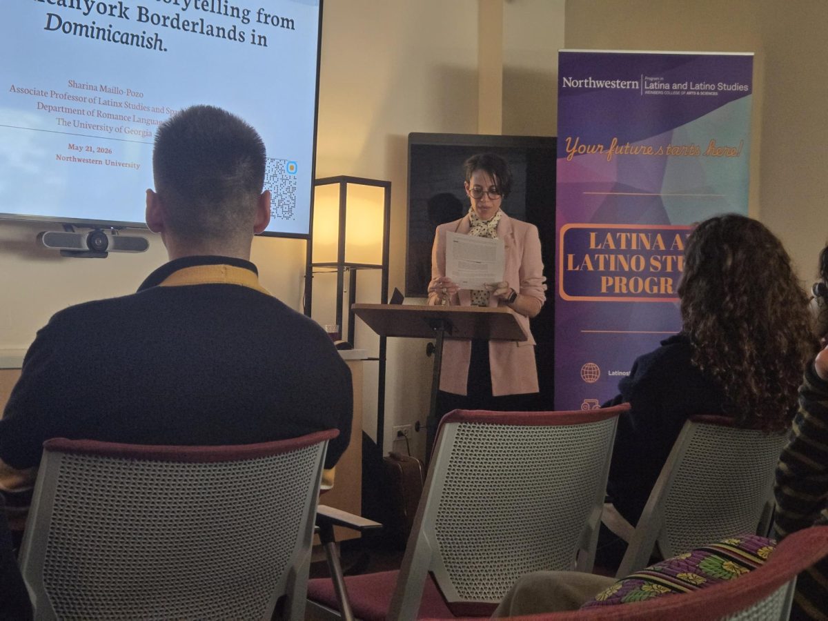 A person standing at a podium in front of a slideshow, speaking to a crowd