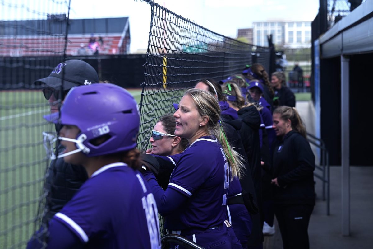 Players in purple jerseys cheer on their team through a net.