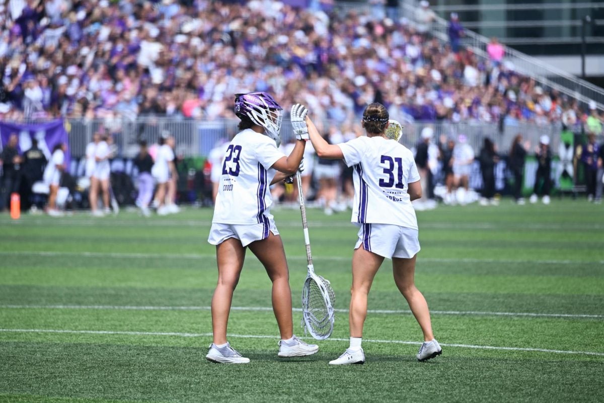 Two players in white jerseys high five.