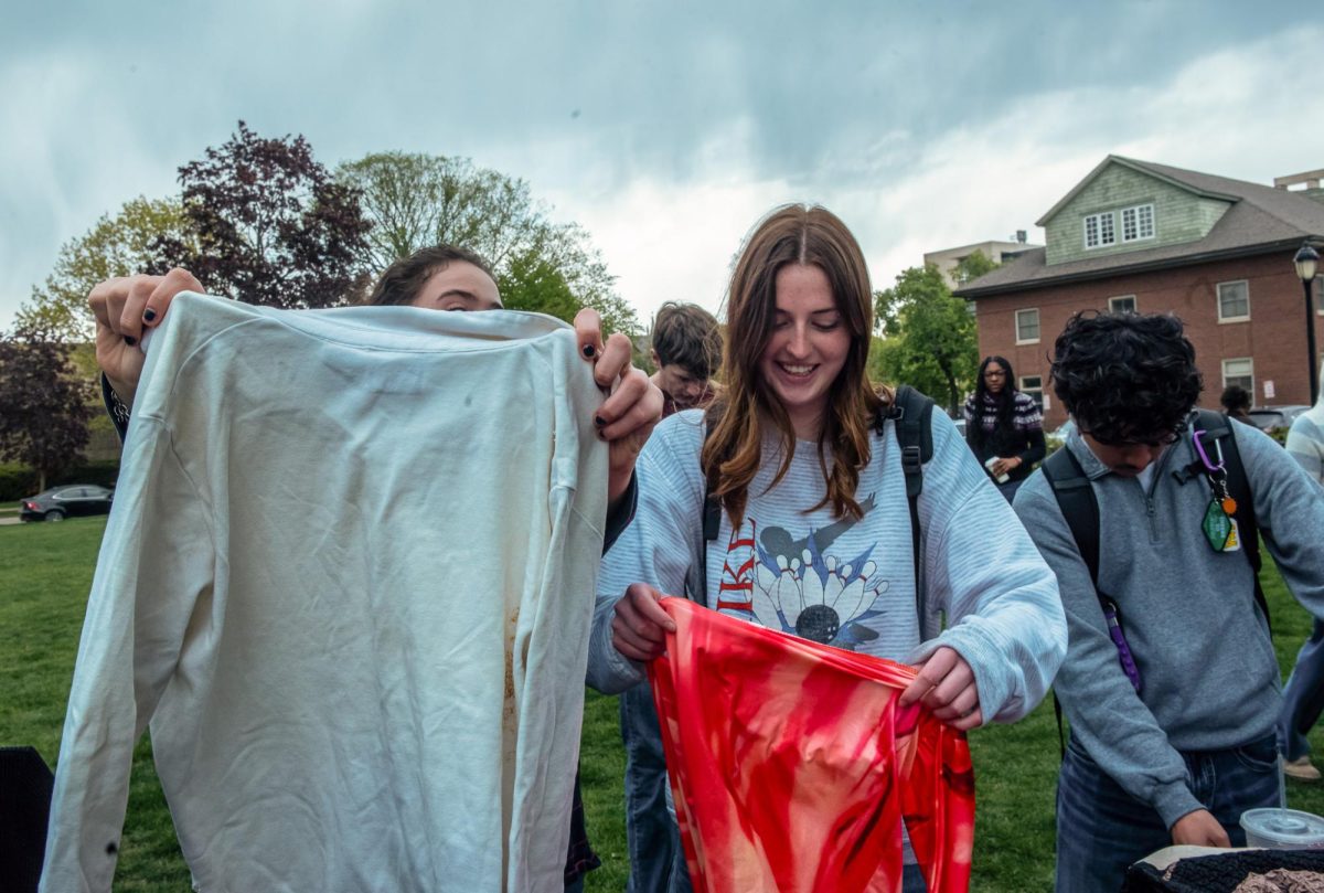 Two shoppers lift up and examine shirts. 