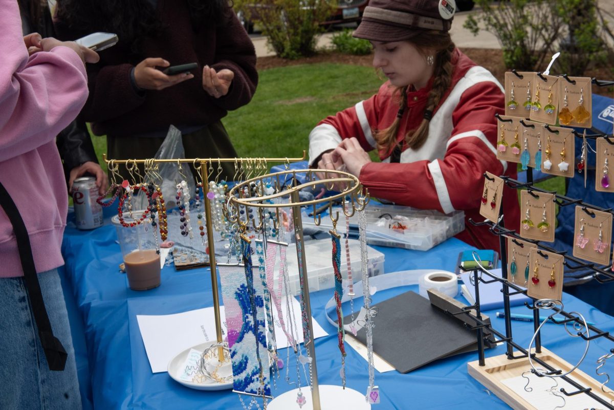 People point at and touch jewelry displayed on a table. 