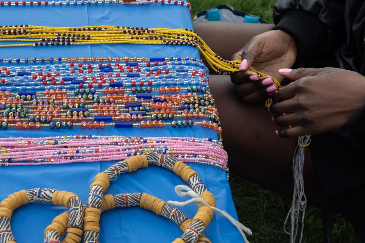 Two people viewing waistbeads on a table.