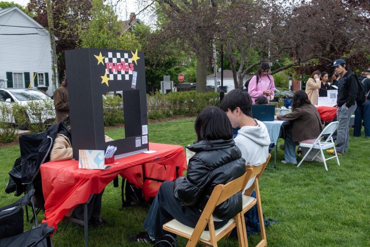 People at a table with a photo sign amongst several tables on the lawn.