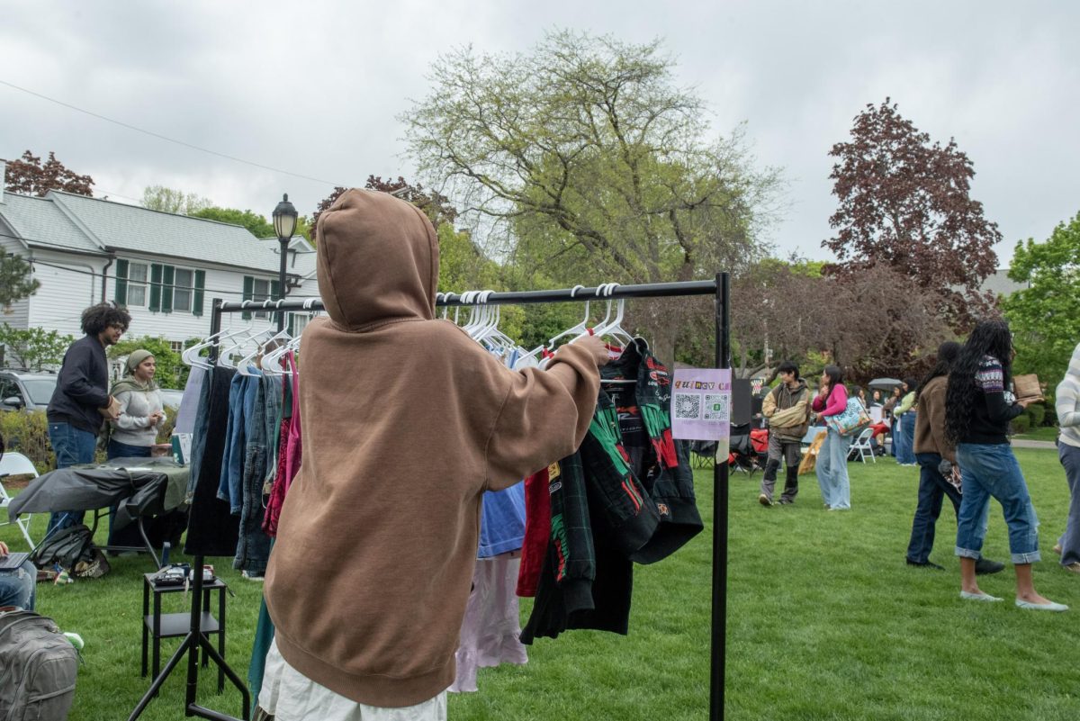 Person adjusting clothing on a rack facing a passerby.