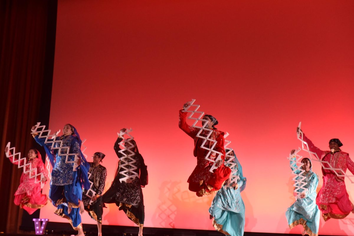 A group of dancers jumping with props in their hands