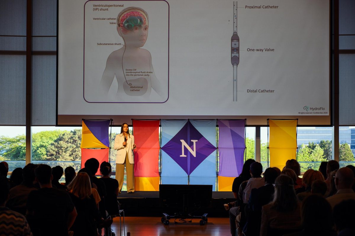 A person wearing white speaks to the audience from the stage.
