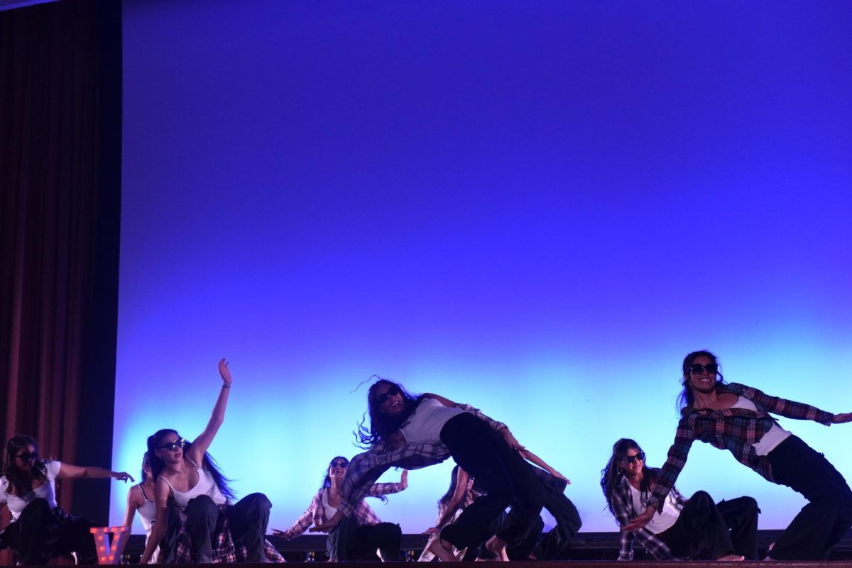 A group of dancers with one hand on the ground