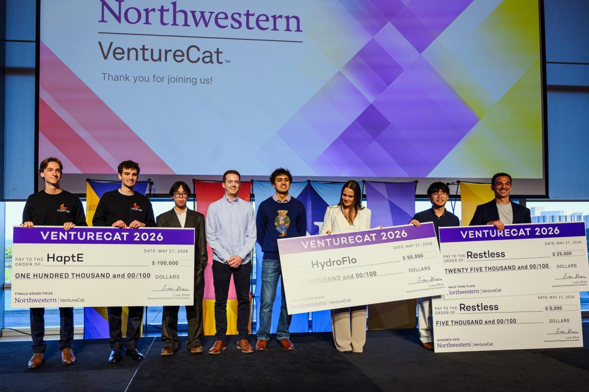 People stand on stage, some holding large checks.