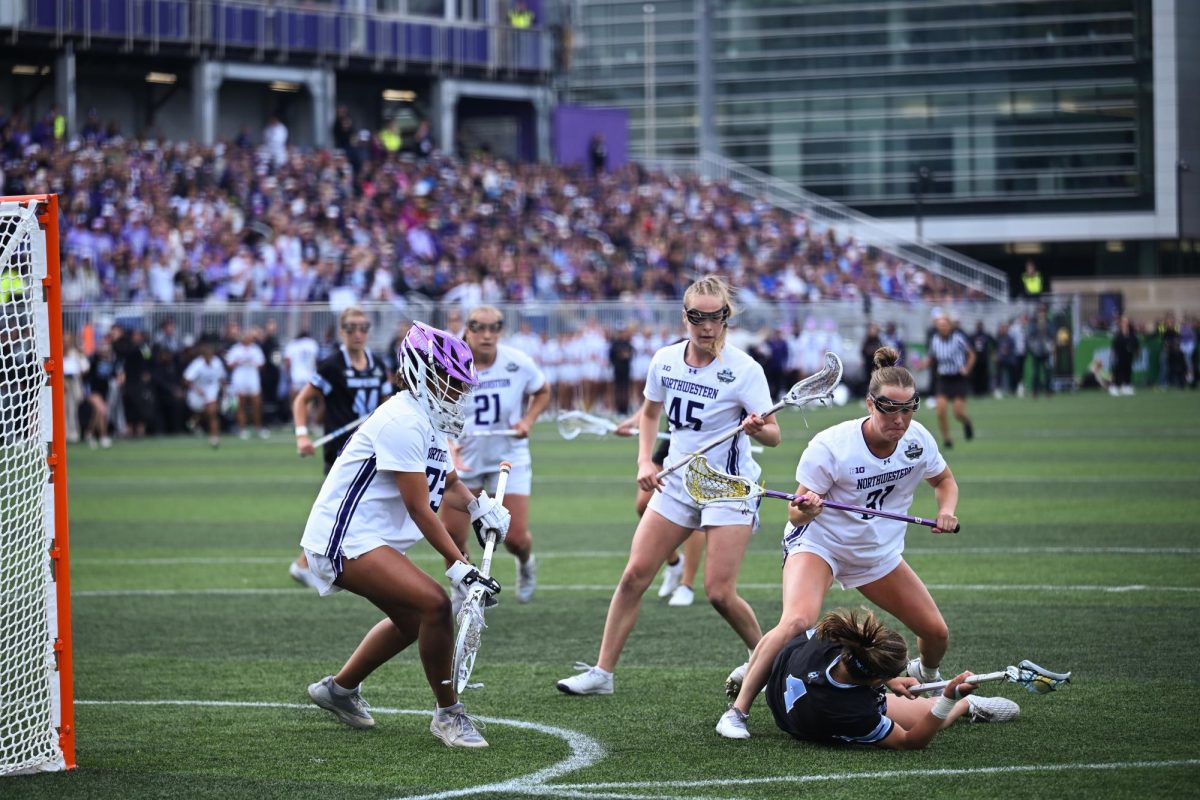 Players in white surround a goal while a player in black lies on the ground.