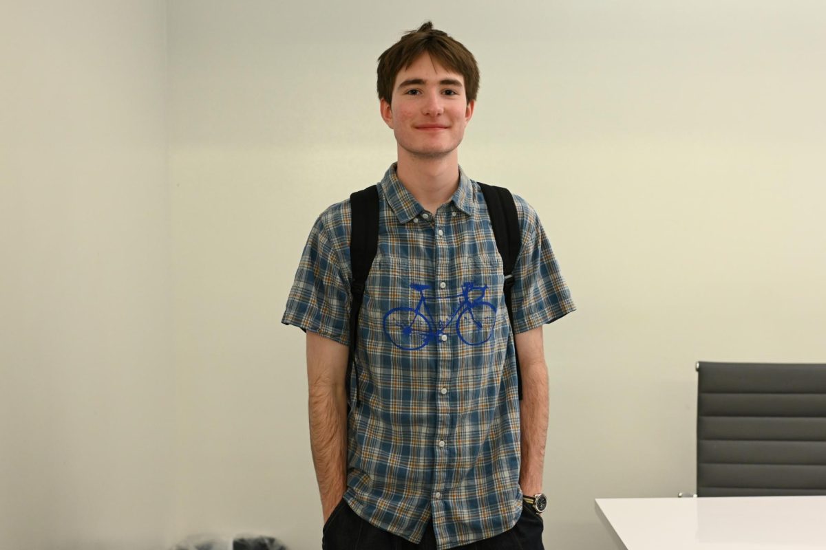 A person with a checkered pattern shirt with a bike on it smiles for a photo.