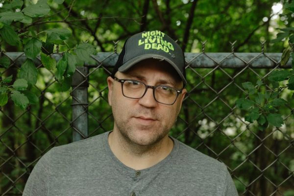 A person in a hat looks at the camera.